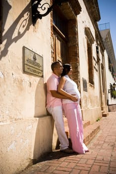 Side profile of a mid adult man embracing a pregnant young woman from behind, Santo Domingo, Dominican Republic