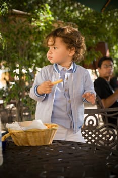 Baby boy standing on a chair with a French fry in his hand, Santo Domingo, Dominican Republic