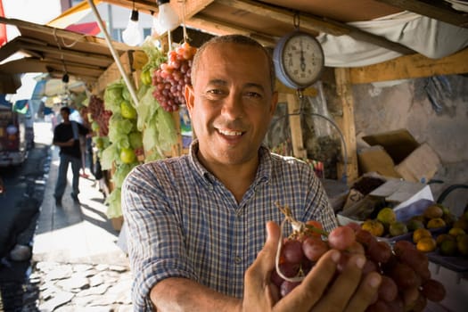 Portrait of a mature man holding a bunch of red grapes, Santo Domingo, Dominican Republic