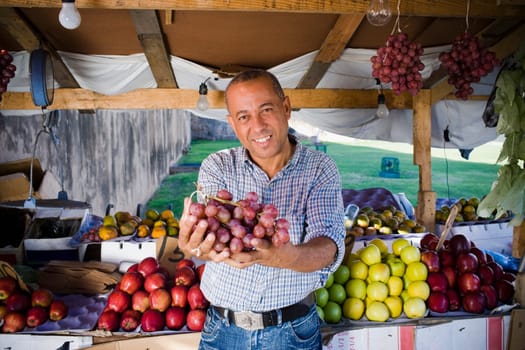 Portrait of a mature man holding a bunch of red grapes, Santo Domingo, Dominican Republic