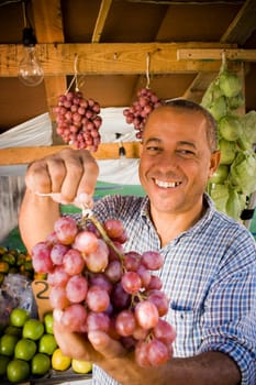Portrait of a mature man holding a bunch of red grapes, Santo Domingo, Dominican Republic