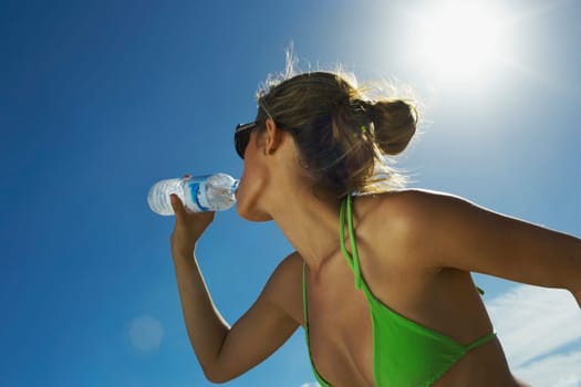 Young woman drinking water on beach