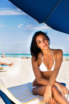 Young woman sitting on lounge chair on beach