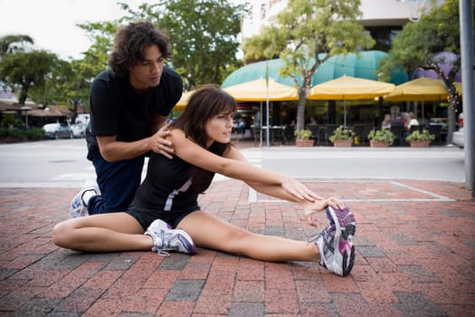 Young woman stretching with physical trainer