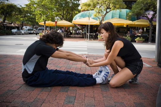 Young man stretching with physical trainer