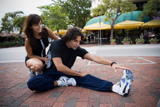 Young man stretching with physical trainer