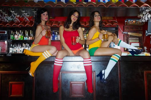 Three sexy young waitresses sitting on bar counter