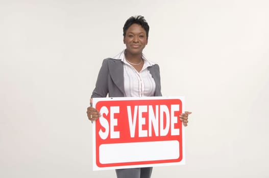 Real Estate agent holding a For Sale (Se Vende) sign