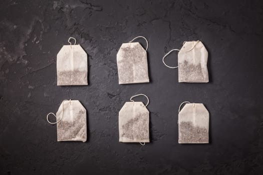 Assorted tea bags on black stone background