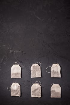 Assorted tea bags on black stone background