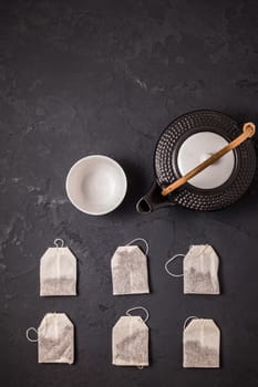 Assorted tea bags with tea pot and cup on black stone background