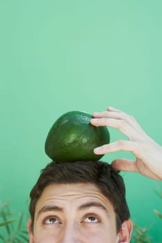 Young man balancing an avocado on his head