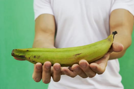 Young man holding a green plantain