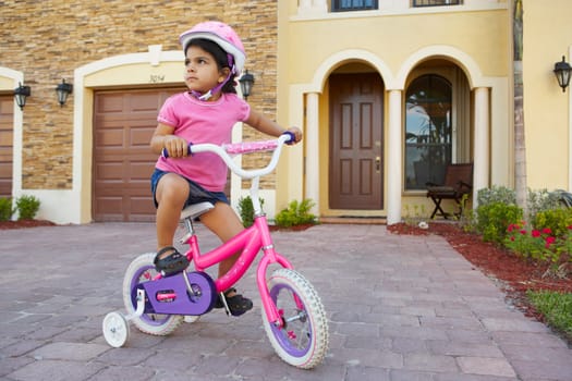 Girl riding a bicycle in front of a house