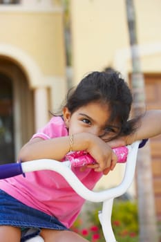 Close-up of a girl leaning on the handlebar of a bicycle and looking away