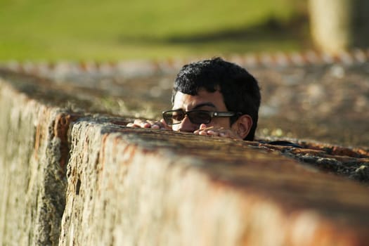 Young man peeking over fence
