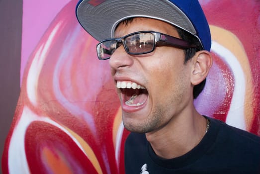 Young man standing in front of graffiti wall