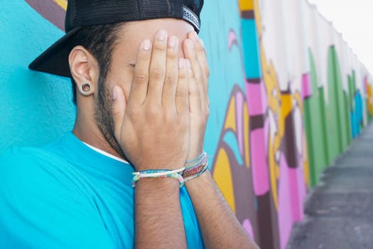 Young man standing in front of graffiti wall