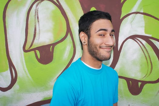Young man standing in front of graffiti wall