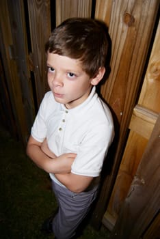 Young boy standing by fence being punished
