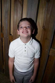 Young boy standing by fence
