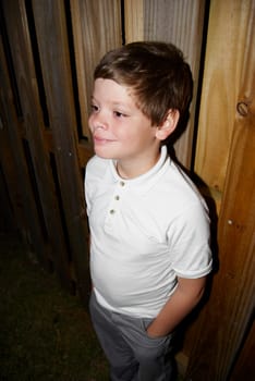 Young boy standing by fence