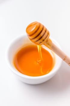 Honey with wooden honey dipper on white background