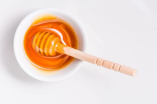 Honey with wooden honey dipper on white background