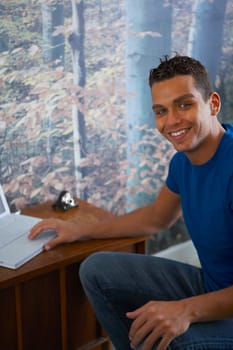 Portrait of a young man using a laptop and smiling