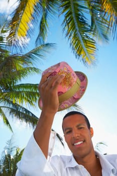 Portrait of a young man holding a hat above his head and smiling