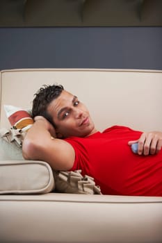 Portrait of a young man lying on a couch and holding a mobile phone