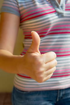 Mid section view of a woman making a thumbs up sign