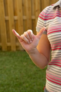 Mid section view of a woman making a shaka sign