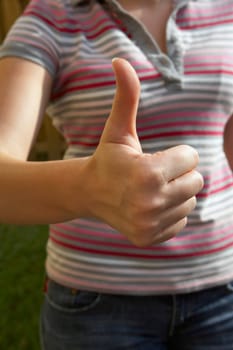 Mid section view of a woman making a thumbs up sign