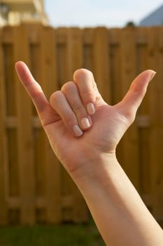 Close-up of a woman's hand making a shaka sign