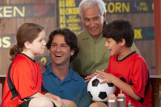 Boy holding a soccer ball with his family beside him in a restaurant
