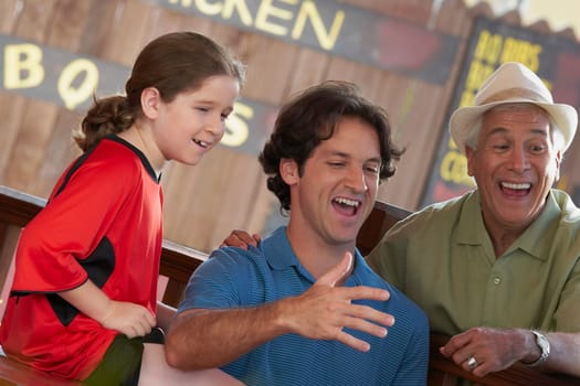 Side profile of a girl with her father and grandfather sitting in a restaurant