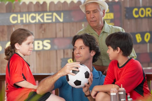 Mid adult man playing with his children in a restaurant with his father standing behind him