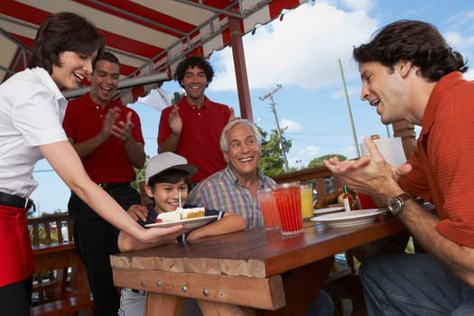 Boy celebrating his birthday with his father and grandfather in a restaurant