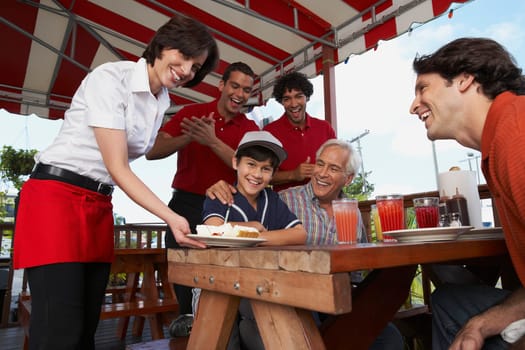 Portrait of a boy celebrating his birthday with his father and grandfather in a restaurant