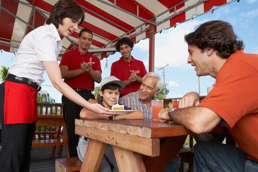 Boy celebrating his birthday with his father and grandfather in a restaurant