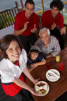 Portrait of a young woman serving dessert to a boy celebrating his birthday in a restaurant