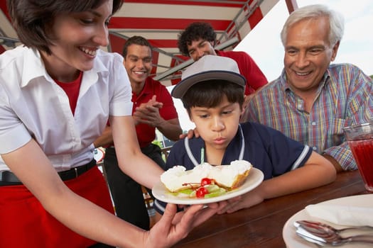 Boy celebrating his birthday with his grandfather in a restaurant