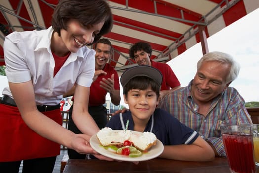 Portrait of a boy celebrating his birthday with his grandfather in a restaurant