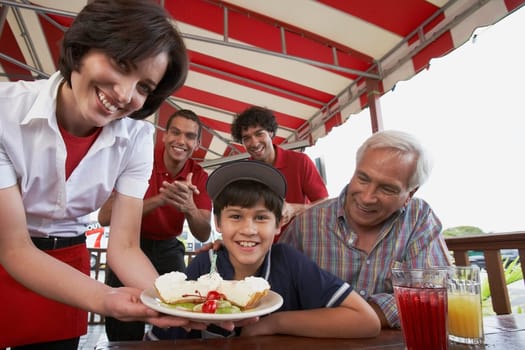 Portrait of a boy celebrating his birthday with his grandfather in a restaurant