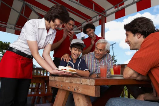 Boy celebrating his birthday with his father and grandfather in a restaurant