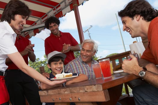 Boy celebrating his birthday with his father and grandfather in a restaurant