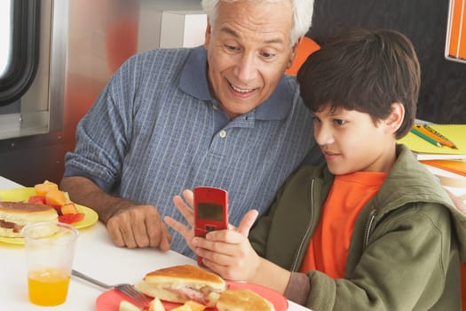 Boy teaching his grandfather how to use a mobile phone