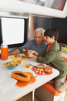Side profile of a boy teaching his grandfather how to use a mobile phone