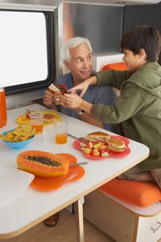 Side profile of a boy teaching his grandfather how to use a mobile phone